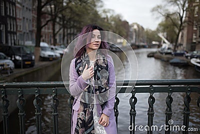 Girl in the coat enjoying city. Young woman looking to the side on Amsterdam channel, Netherlands Stock Photo