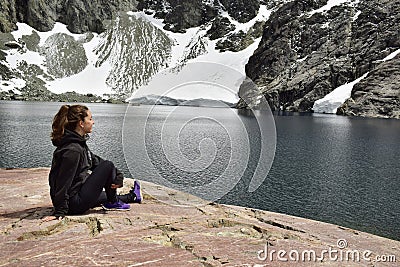 A girl contemplates the mountains and the glaciers that fall to a lake Stock Photo