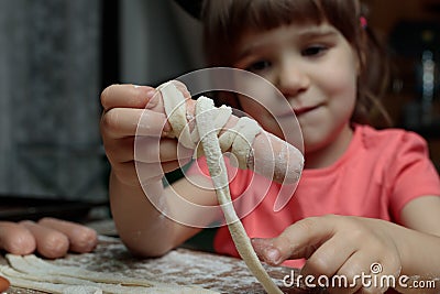 A little girl is preparing a treat for Halloween- mummy sausages. Selective focus. Cooking workshops for children Stock Photo