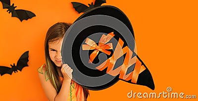 The girl covers one eye with a witch`s hat with a cunning sinister face Stock Photo
