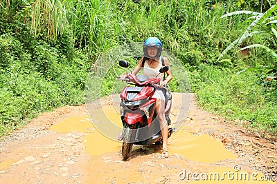 Girl crossing muddy pond on motorbike Stock Photo