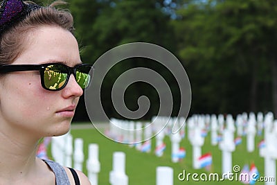 Girl crying in cemetery with reflection of tombstones in her glasses Editorial Stock Photo