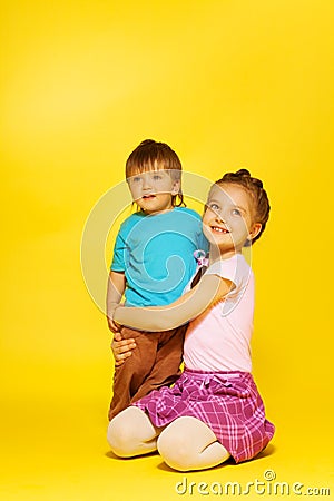 Girl cuddle standing child while sitting on floor Stock Photo