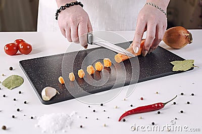 Girl cuts carrots into small slices on a black cutting board Stock Photo