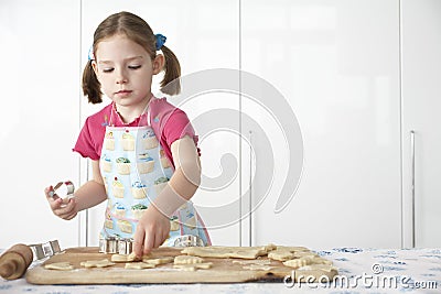 Girl (5-6) cutting dough on board in kitchen Stock Photo