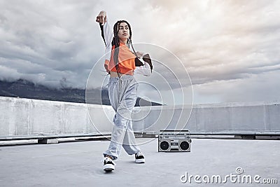Girl, dance and hip hop outdoor on city rooftop with music, speaker and cool gen z streetwear fashion. Woman, moving and Stock Photo