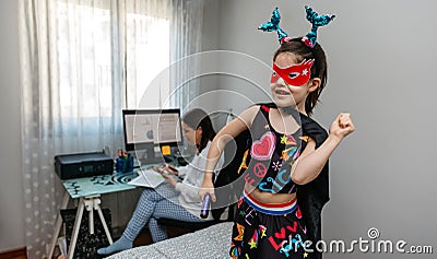 Girl dancing in disguise while her mother teleworking Stock Photo