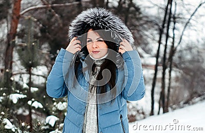 Girl with dark hair with natural silver fox fur posing in a snowy forest. Stock Photo