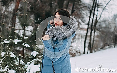 Girl with dark hair with natural silver fox fur posing in a snowy forest. Stock Photo