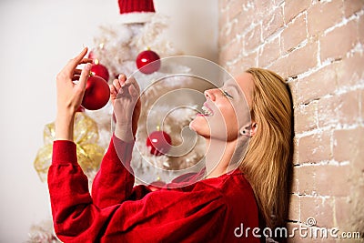 Girl decorate christmas tree with ornaments. Waiting for christmas. Girl wear red dress sit near christmas tree. Woman Stock Photo