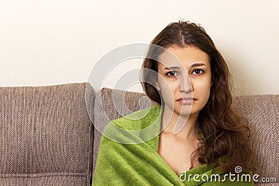 A girl in despair sit on a beige sofa. Frustrated young woman head frowning looking unhappy and stressful Stock Photo