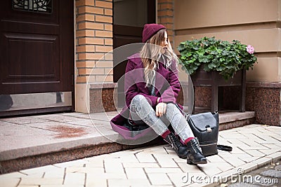 The girl in despair sits on the threshold of the house. Bad luck and depression Stock Photo