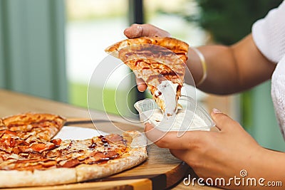 A girl dips a slice of pizza in sauce Stock Photo