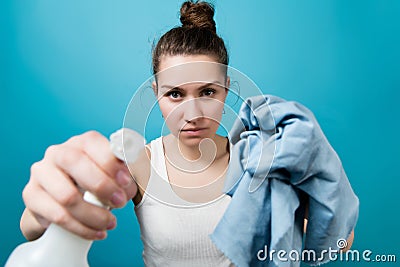 Girl directs a spray bottle of cleaning agent into camera and holds out a rag Stock Photo