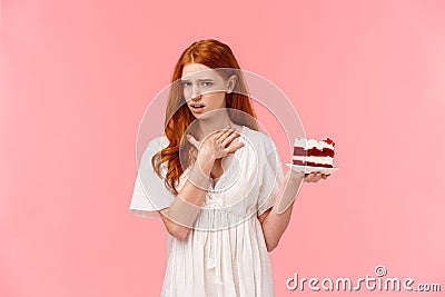 Girl dislike dessert, express aversion and disappoinment, touching neck as willing puke from awful tasty. Ignorant Stock Photo