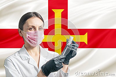 Girl doctor prepares vaccination against the background of the Guernsey flag. Vaccination concept Guernsey Stock Photo