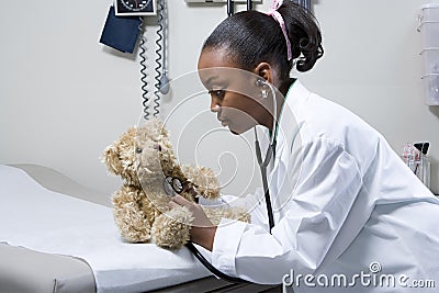 Girl doctor using stethoscope on teddy bear Stock Photo