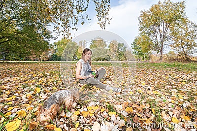 Beautiful young girl with her Yorkshire terrier dog puppy enjoying and playing in the autumn day in the park selective focus Stock Photo