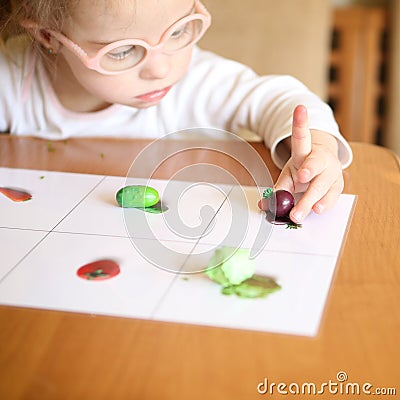 Girl with Down syndrome is involved in sorting vegetables Stock Photo