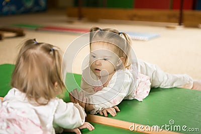 Girl with Down syndrome looks at his reflection in the mirror Stock Photo