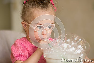 Girl with Down syndrome makes breathing speech therapy exercise Stock Photo