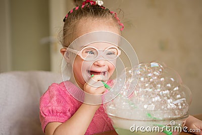 Girl with Down syndrome makes breathing speech therapy exercise Stock Photo