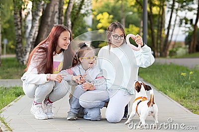 A girl with Down syndrome plays with her sisters while walking the dog Jack Russell Stock Photo
