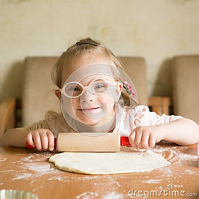 Girl with down syndrome unrolls dough Stock Photo