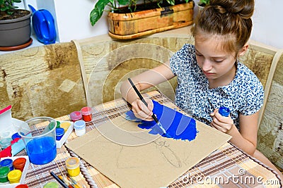 A girl drawing blue gouache cardboard, artistic creation at home, makes creative artwork Stock Photo