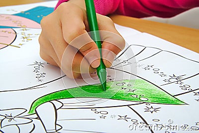 Girl drawing with a green crayon in classroom Stock Photo