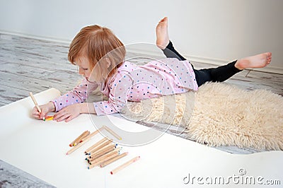 Girl draws with colored pencils lying on the floor Stock Photo