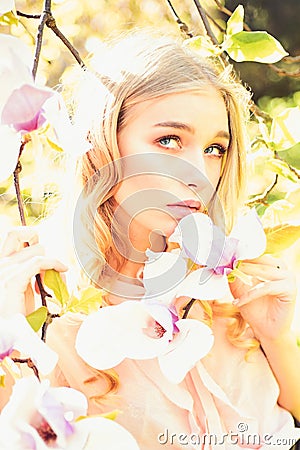 Girl on dreamy face, tender blonde near magnolia flowers, nature background. Young woman enjoy flowers in garden. Lady Stock Photo