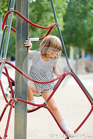 Girl in dress climbing on ropes Stock Photo