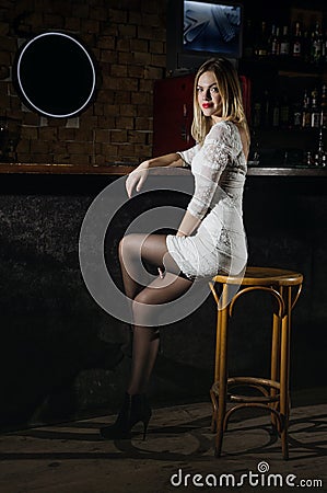 Girl in a dress and pantyhose sits in the bar Stock Photo