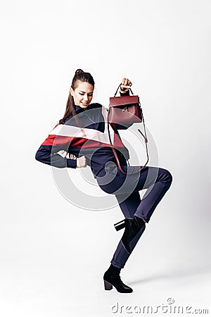 Girl dressed in sporty blue suit with a red and white print on a sweatshirt and heels poses with bag in her hands on the Stock Photo