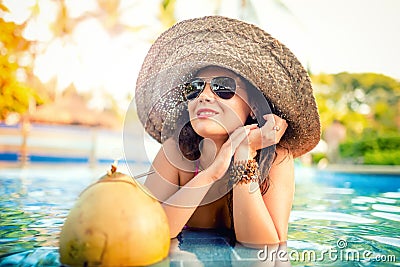 Girl drinking coconut cocktail, attractive and young woman having refreshment drink in pool Stock Photo