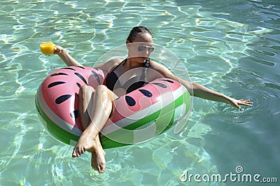 Girl drinking orange juice on watermellon float Stock Photo