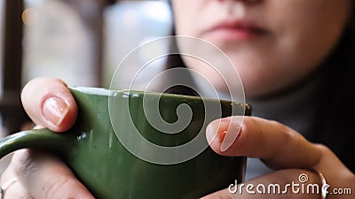 Girl drinks a hot drink in the morning. A woman holds a cup of tea or coffee near her lips. Reusable ceramic green cup Stock Photo