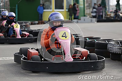 Girl is driving Go-kart car with speed in a playground racing track. Stock Photo