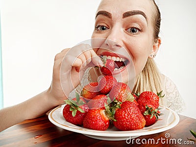 Girl eagerly eating strawberries on white background Stock Photo