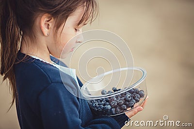 The girl eating blueberries from a glass bowl Stock Photo