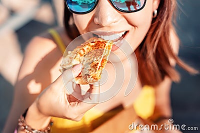 Girl eating Mexican fast food quesadilla on the beach. Healthy and tasty snack Stock Photo