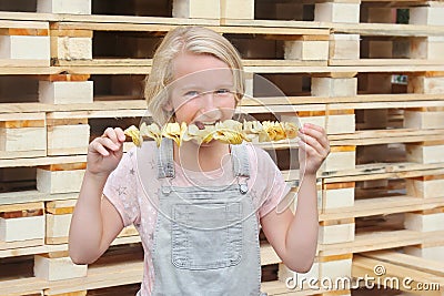 Girl eating potato chips on a stick. Junk food, street food, snack on a walk. Stock Photo