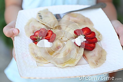 Girl eats dumplings with strawberries Stock Photo