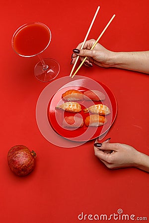 The girl eats sushi on a red plate. Creative concept of restaurant table setting Stock Photo