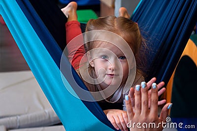 Girl enjoying a sensory therapy on a hammock while physiotherapist assisting her Stock Photo
