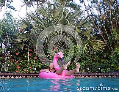 Girl enjoying in the swimming pool on flamingo float Stock Photo