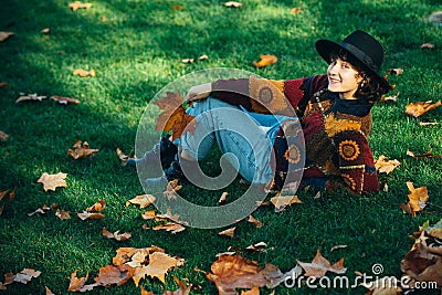 Girl enjoys nature in autumn forest. Woman enjoying fall nature. Smiling girl collects yellow leaves in autumn. Close up Stock Photo