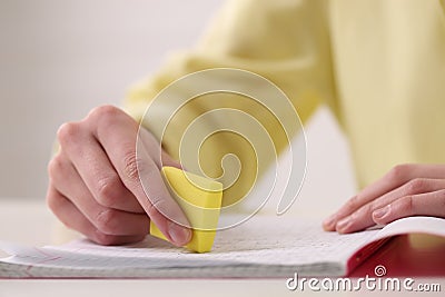 Girl erasing mistake in her notebook at white desk Stock Photo
