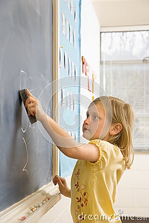 Girl Erasing Writing on Blackboard Stock Photo